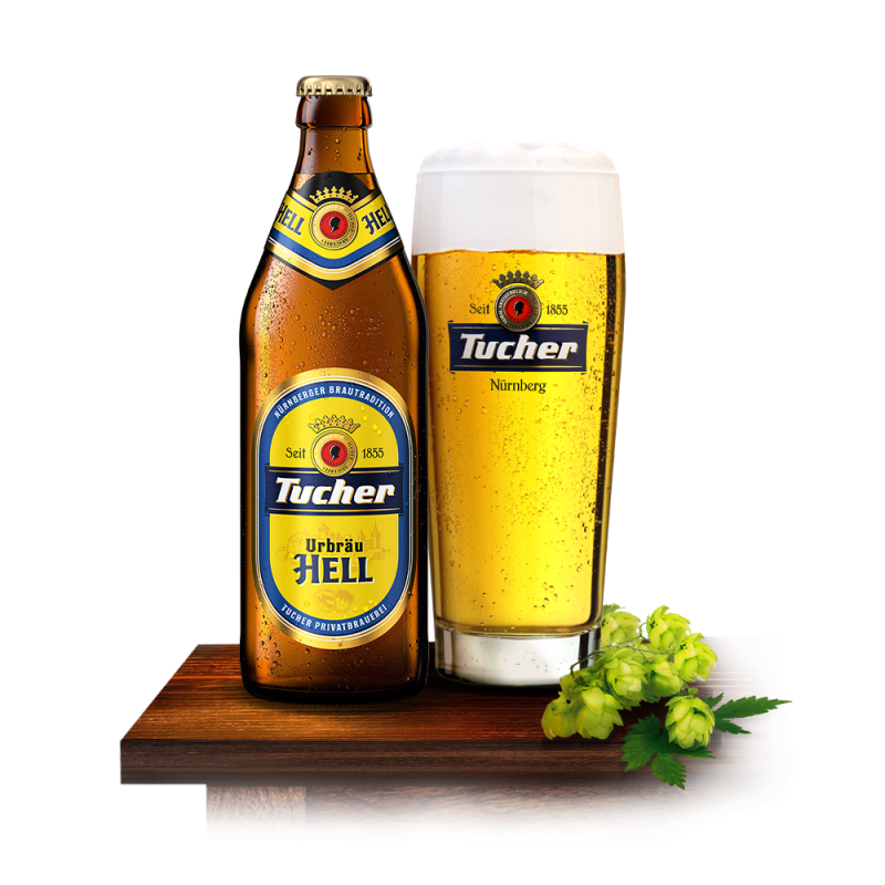 A beer bottle and a full glass stand beside hops sprigs on wood.