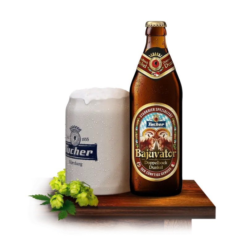 A bottle of dark beer stands next to a full beer glass with foam and hop sprigs on a wooden surface.