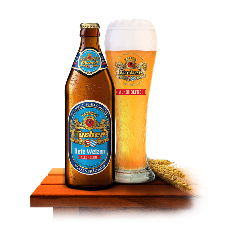 A bottle and a glass of non‑alcoholic wheat beer stand next to a few wheat ears on a wooden table.