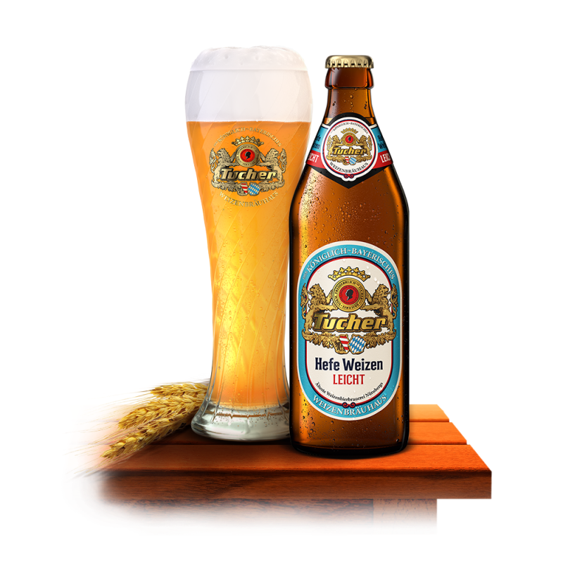 A bottle and a glass filled with light beer stand on a wooden table, next to it lies a barley sprig.