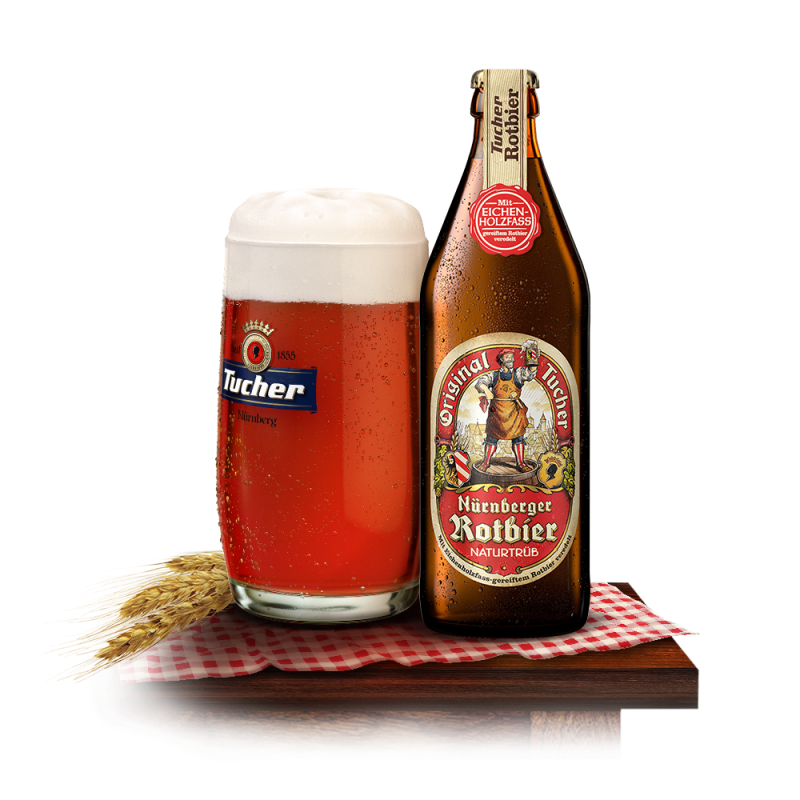 A glass of rotes beer with foam stands next to a filled bottle on a table.