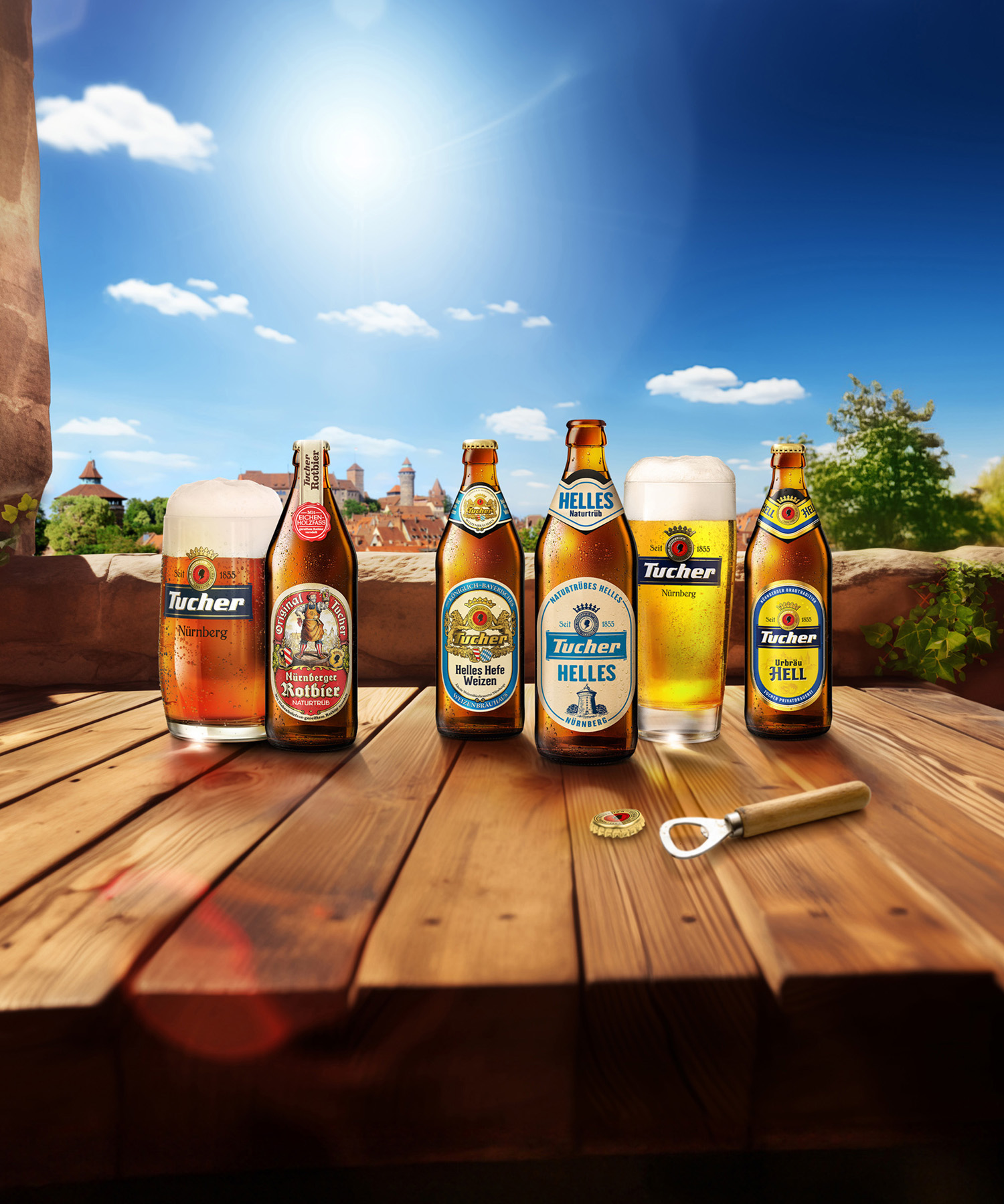 Five bottles and a glass of beer stand on a wooden table in front of a sunny landscape.