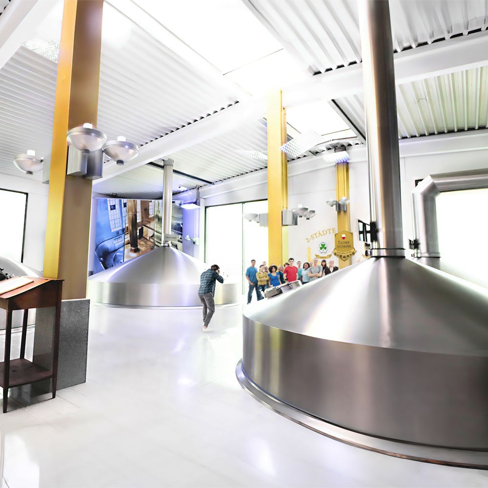 In a brewery, large kettles are visible and people can take a guided tour.